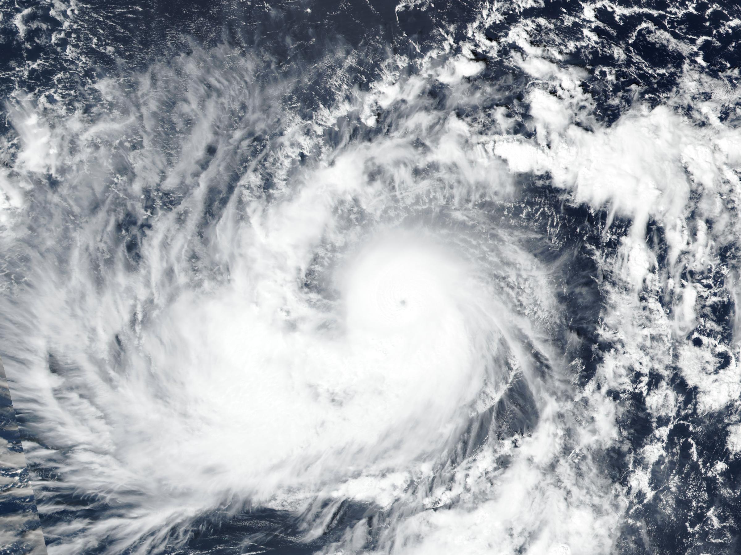 True color satellite view from Suomi NPP VIIRS of Typhoon Champi east southeast of Guam on Oct 17, 2026: a broad spiral of white cloud with a small eye near its center, over dark blue ocean.