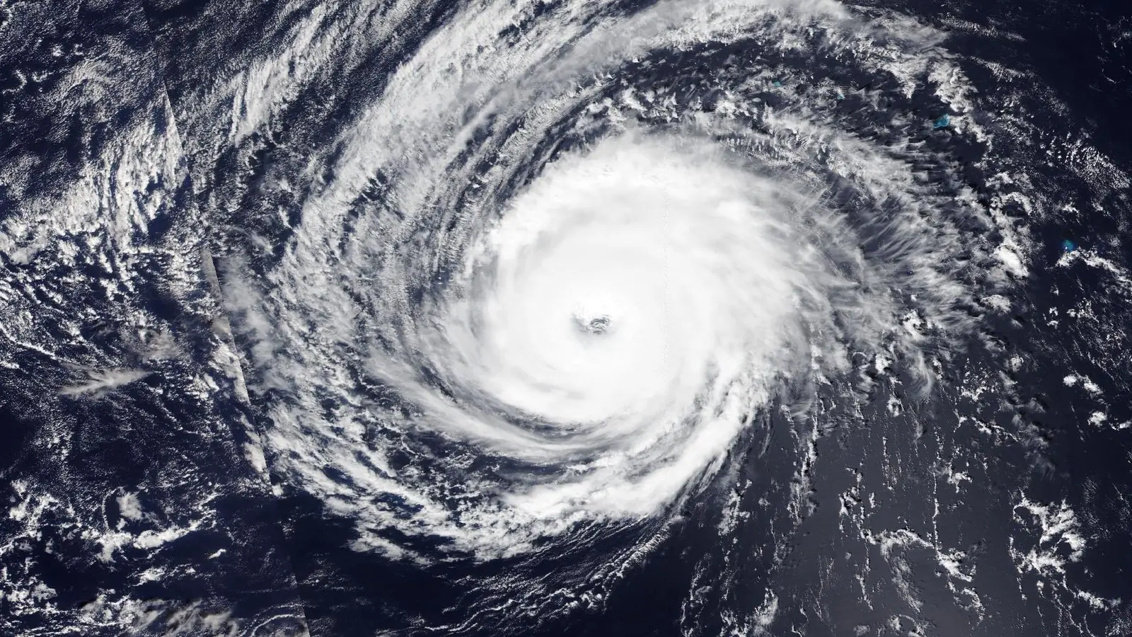NOAA-20 satellite image of Typhoon Nolo at 8:50 PM EDT Oct 4, 2026 (0050 UTC Oct 5): a tight, bright cloud mass with a small clear eye and long spiral bands over the open Pacific, on the International Date Line.